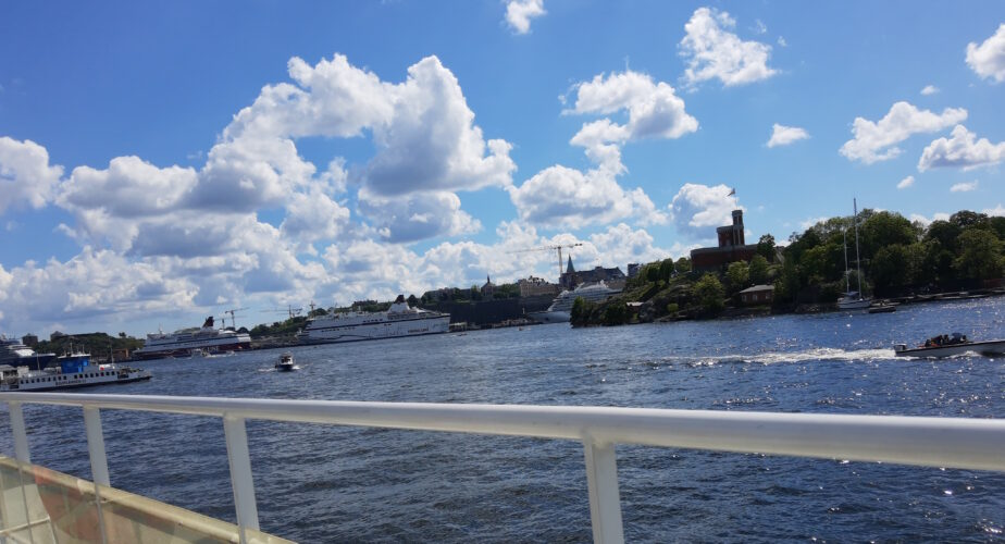 Bild tagen från en färja som är på väg att lämna Stockholm. Cumulosmoln mot blå himmel.