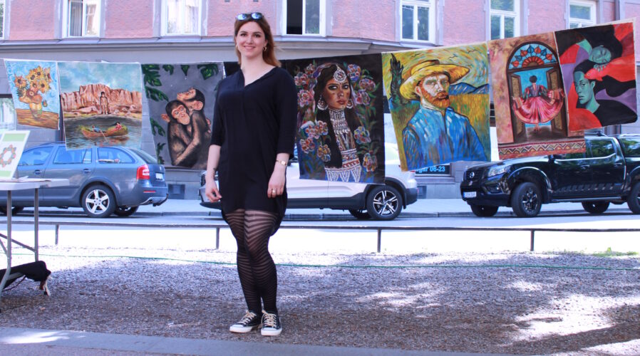 Arghawan står framför den långa raden av hennes målningar.