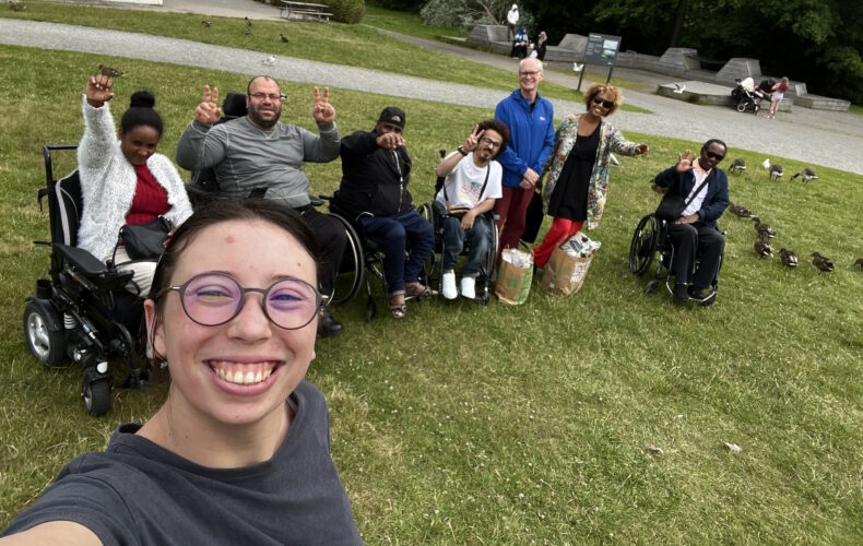 Piage Martin tar en selfie med hela gänget på utflykten till Farsta strandbad bakom sig. Alla skrattar och gör peacetecken mot kameran.